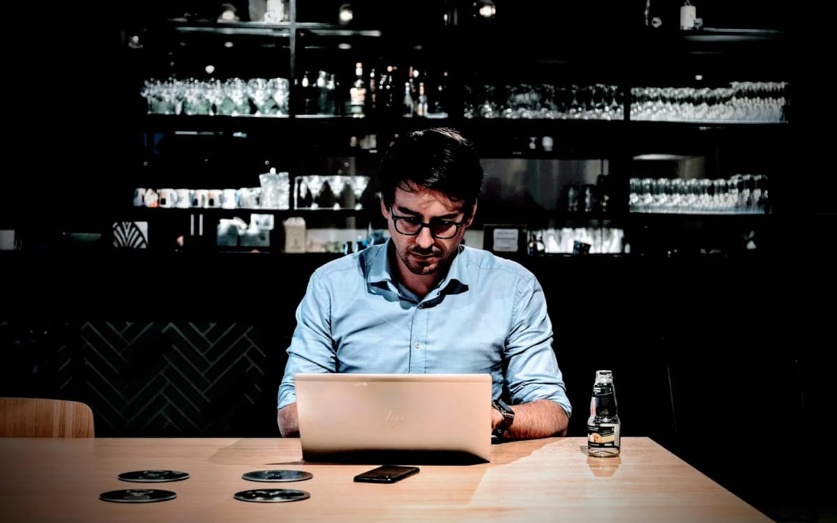 Business owner reading on a laptop at a table in a quiet bar after closing