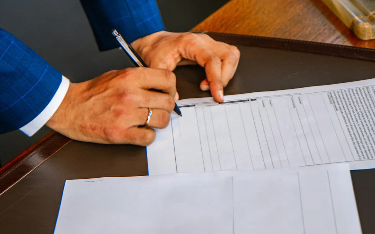 Business owner holding a pen over a printed loan agreement with a second statement below