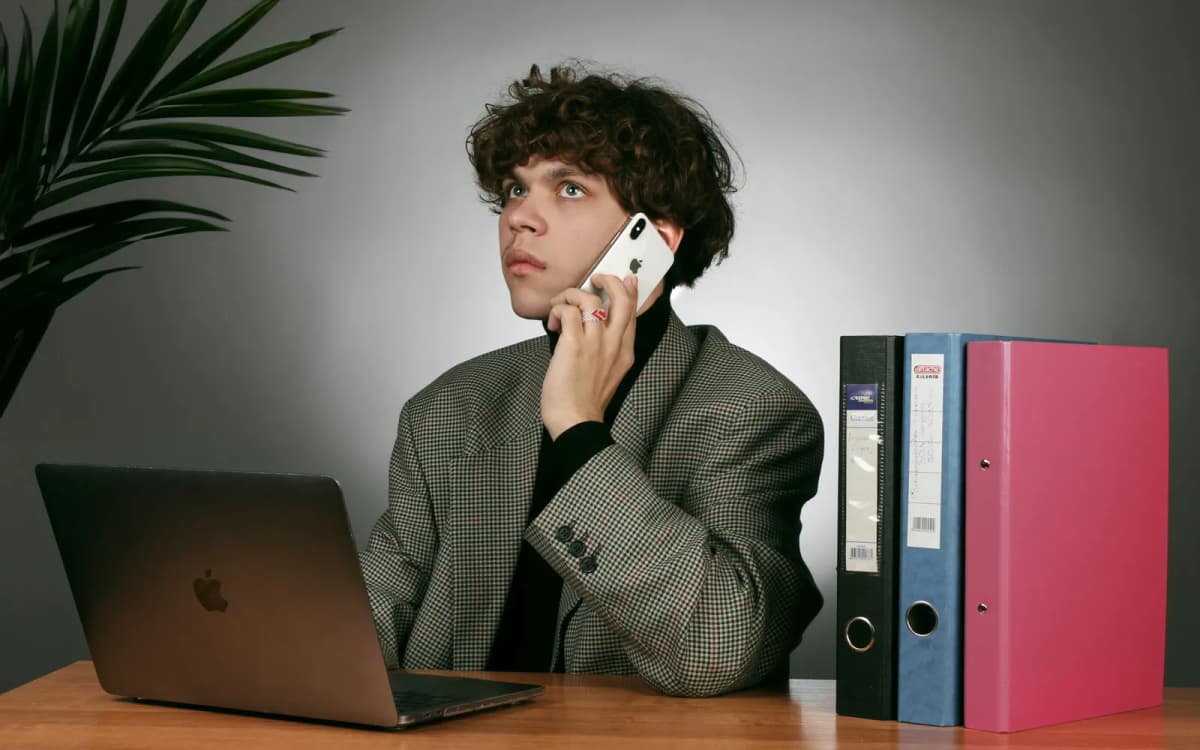 Business owner on a phone call at a desk beside a laptop and binders