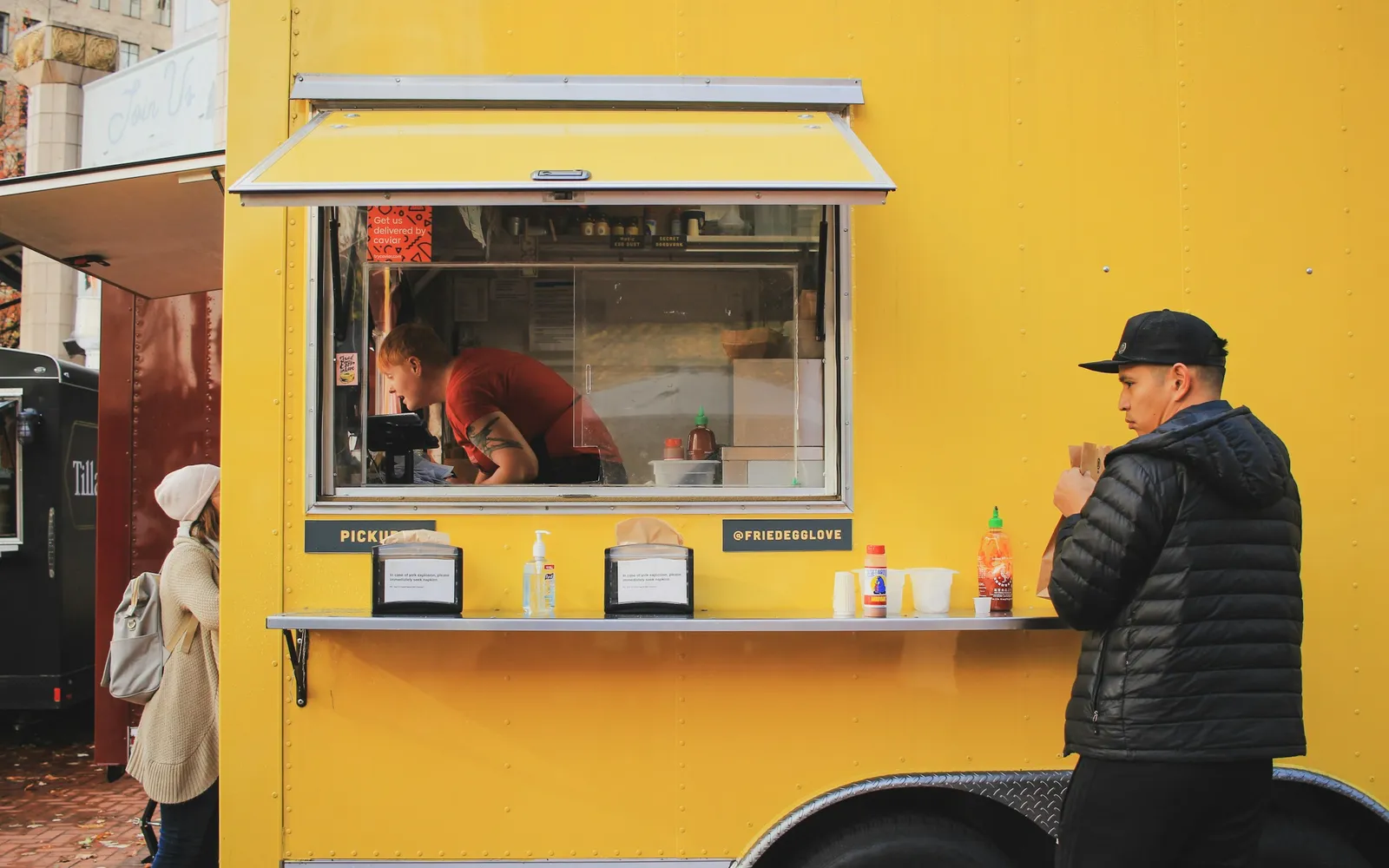 Food truck operator working at the service window while a customer waits at the counter