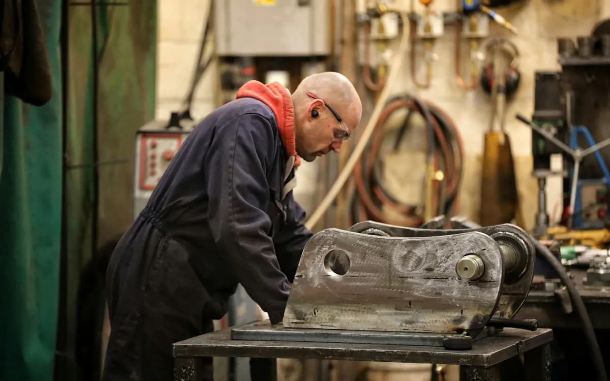 Owner of a small fabrication shop working on a steel part at a workbench