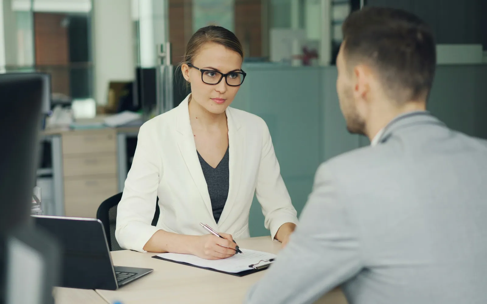 Small business owner sitting across a desk from a banker who is filling in an application form