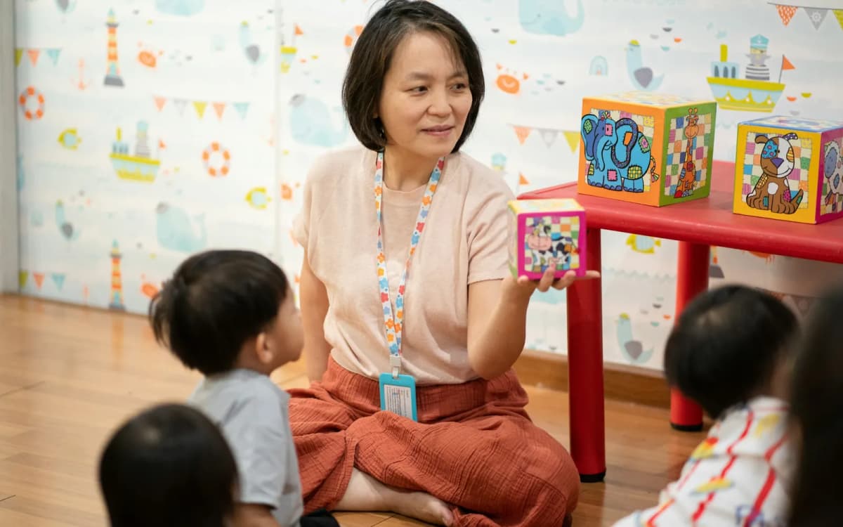 Teacher showing picture blocks to young children in a bright early learning classroom