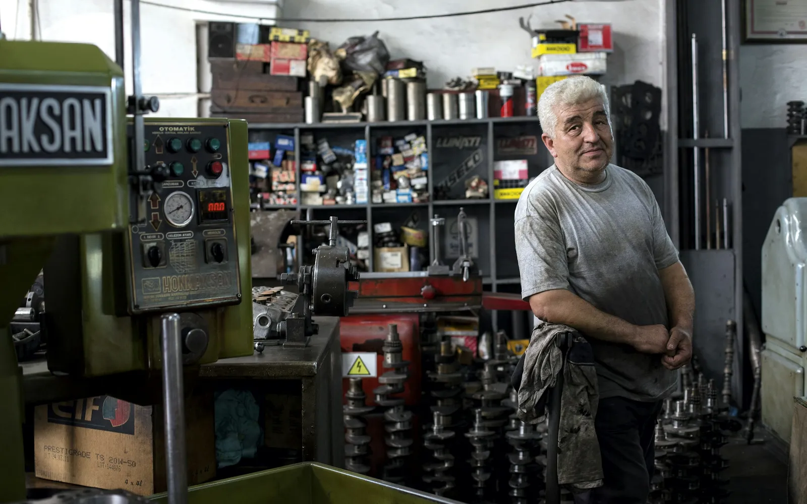 Owner of a small machine shop standing among lathes and tool shelves on the shop floor
