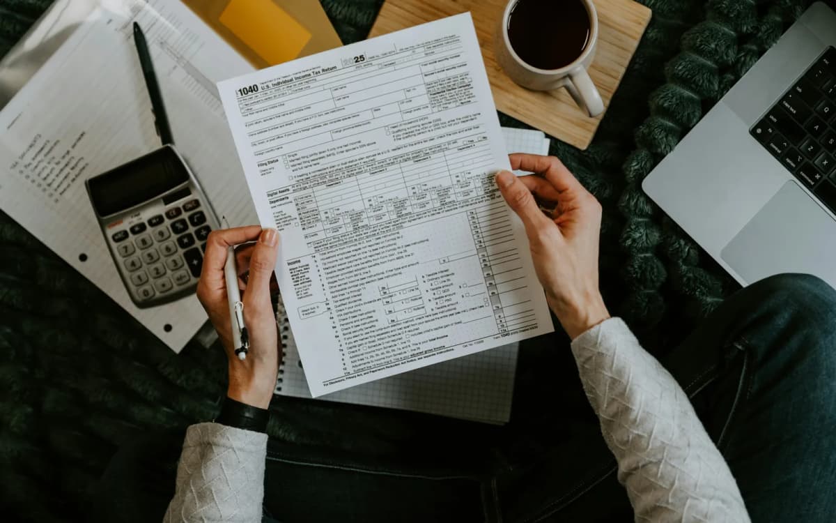 Business owner holding a tax return over a calculator, notebook and laptop