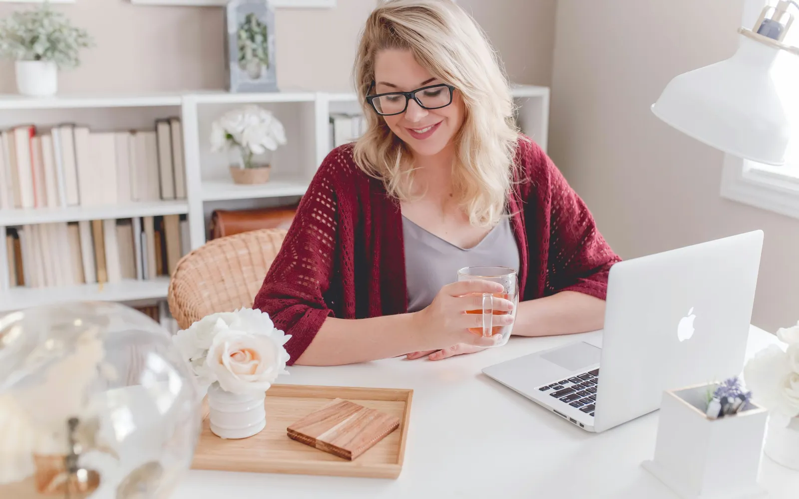 Business owner smiling over a cup of tea while reviewing an account on a laptop