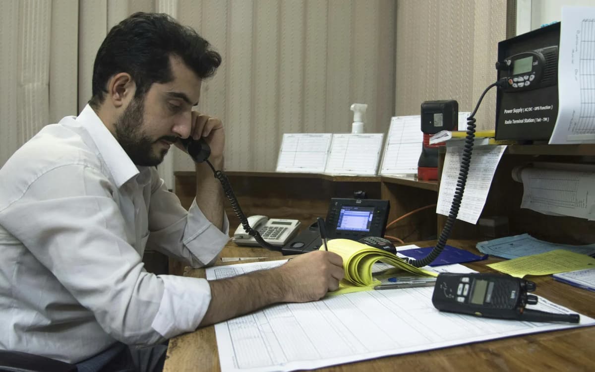Business owner on a phone call taking notes at a desk covered in paperwork