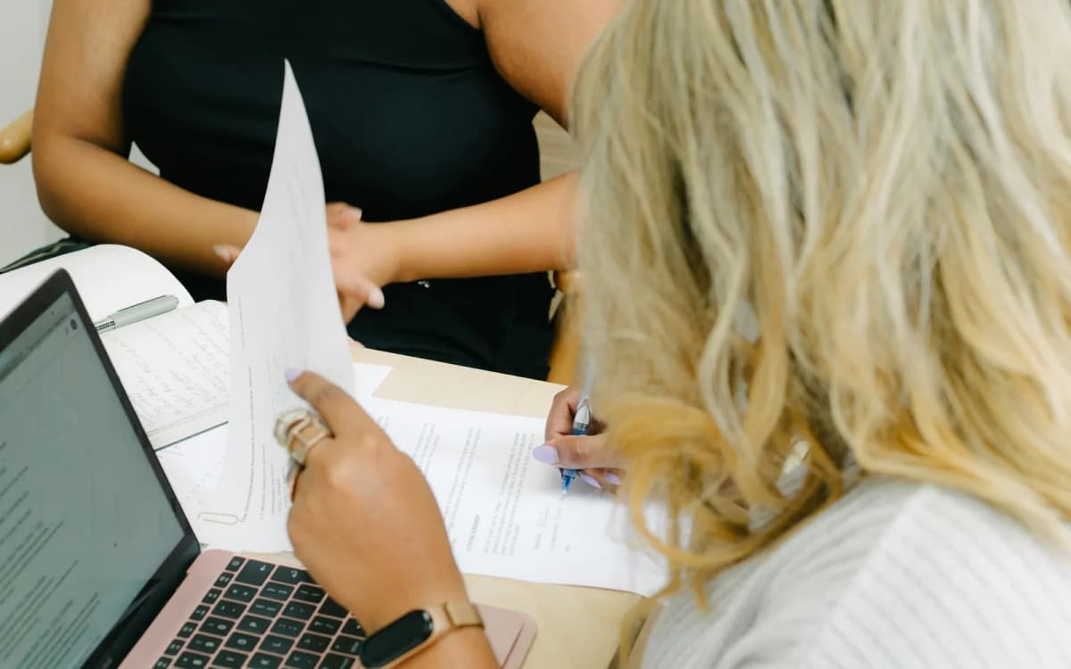 Small business owner reading a printed funding offer beside an open laptop