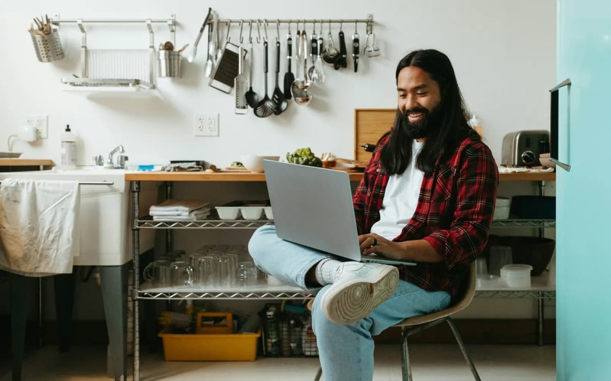 Small business owner checking accounts on a laptop in a home kitchen