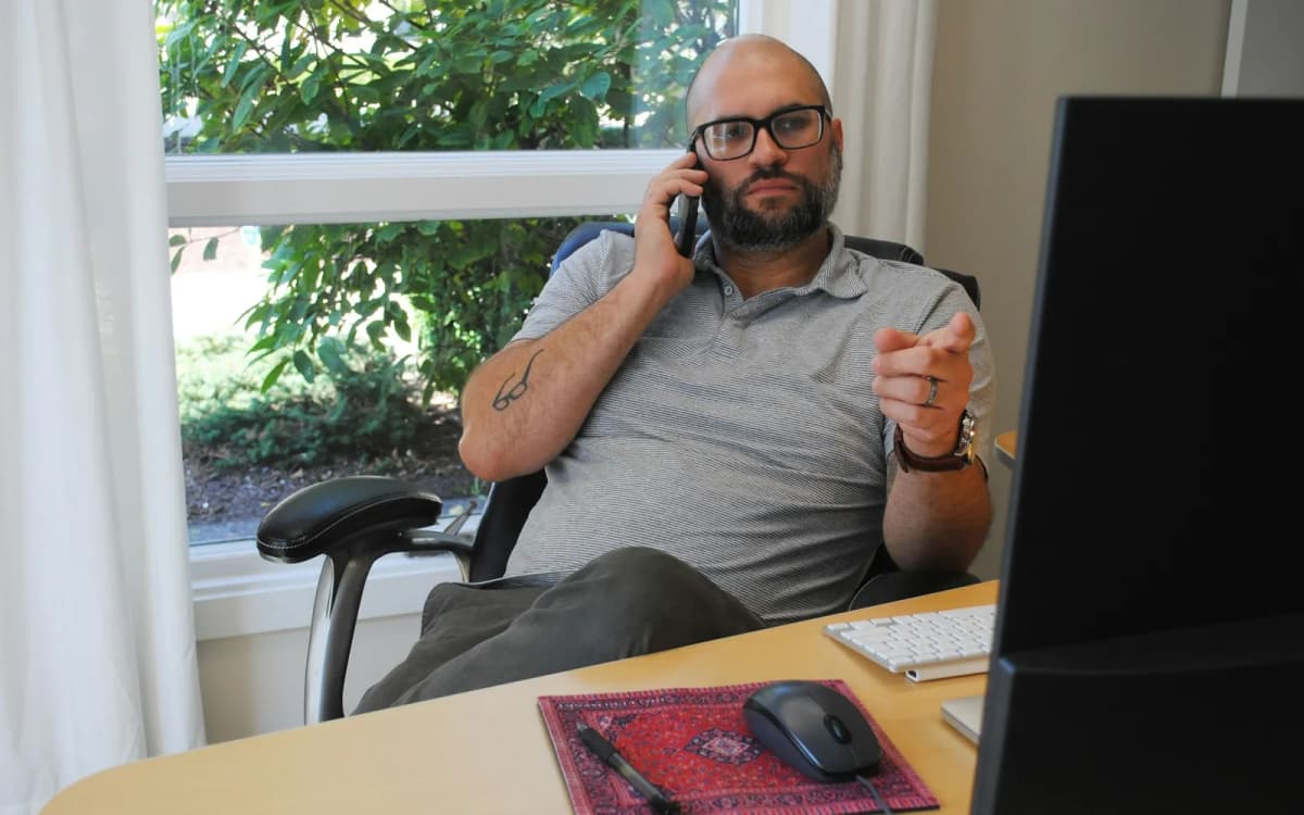 Business owner on a phone call at the desk in a small office by a window