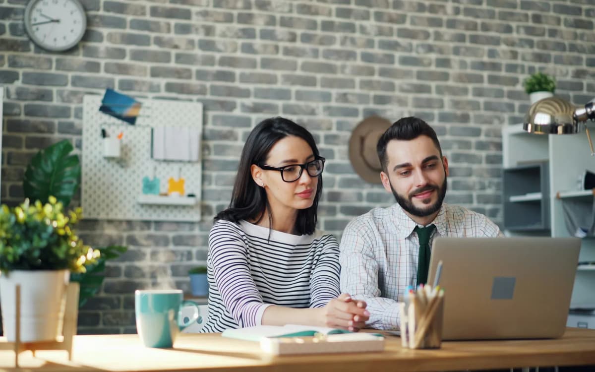Two business owners going over papers and a laptop together at an office desk