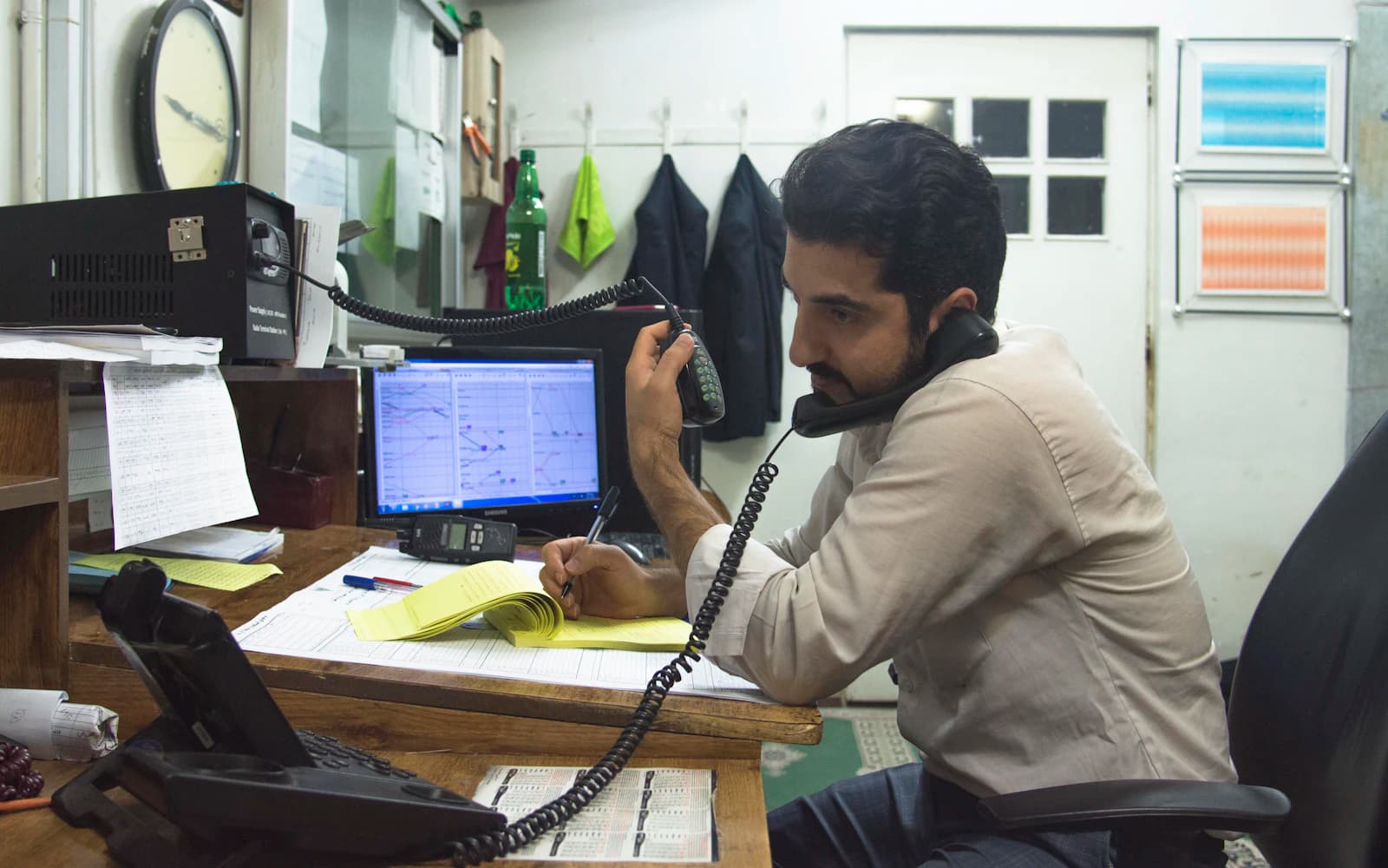 Business owner on a desk phone taking notes in a small workshop office