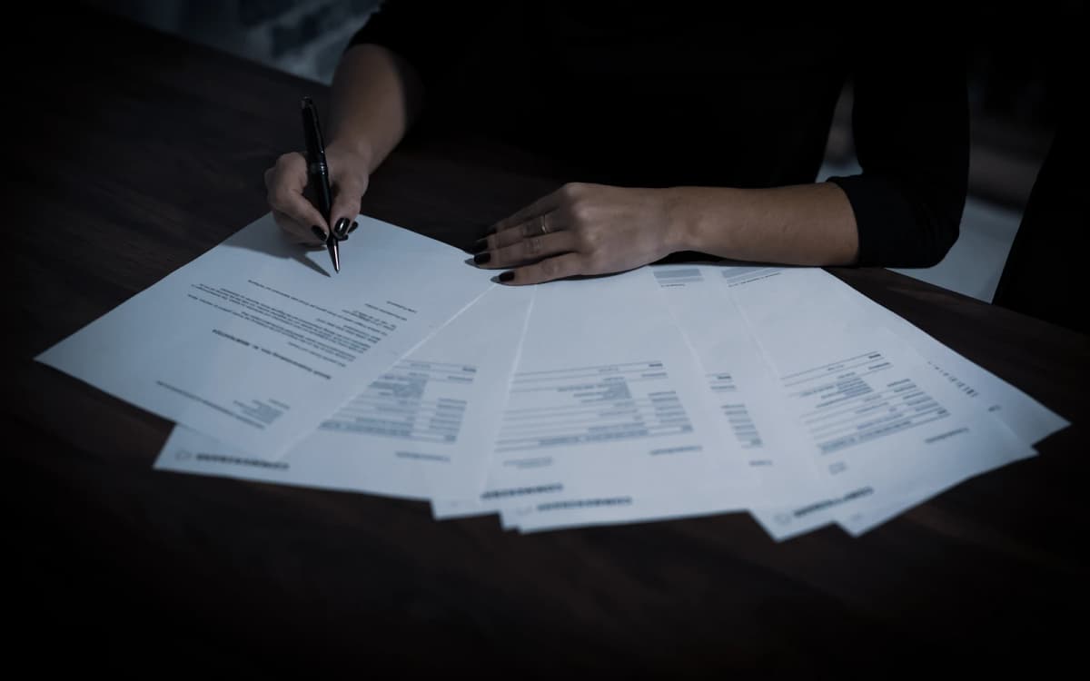 Business owner with a pen reading the pages of a financing agreement spread across a table