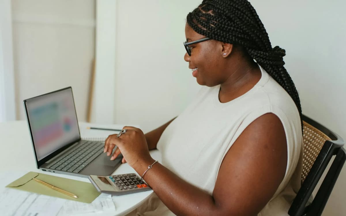 Business owner working through figures on a laptop with a calculator and papers on the table