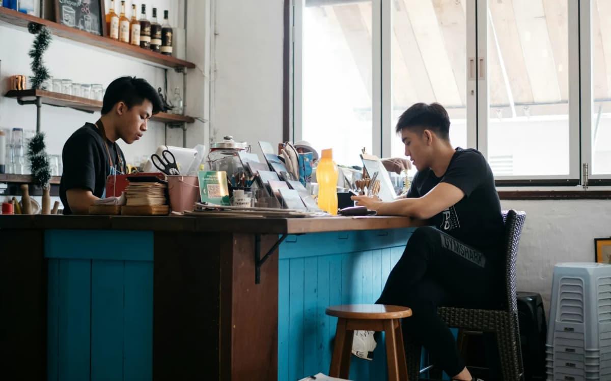 Two business partners at the counter of their cafe, one working on a laptop