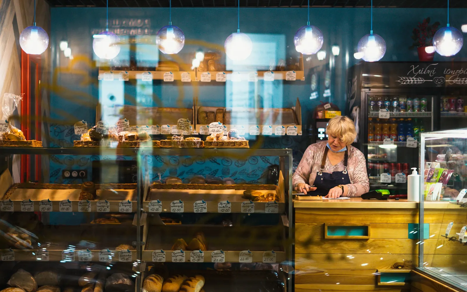Bakery owner writing up the day's figures at the counter behind trays of bread