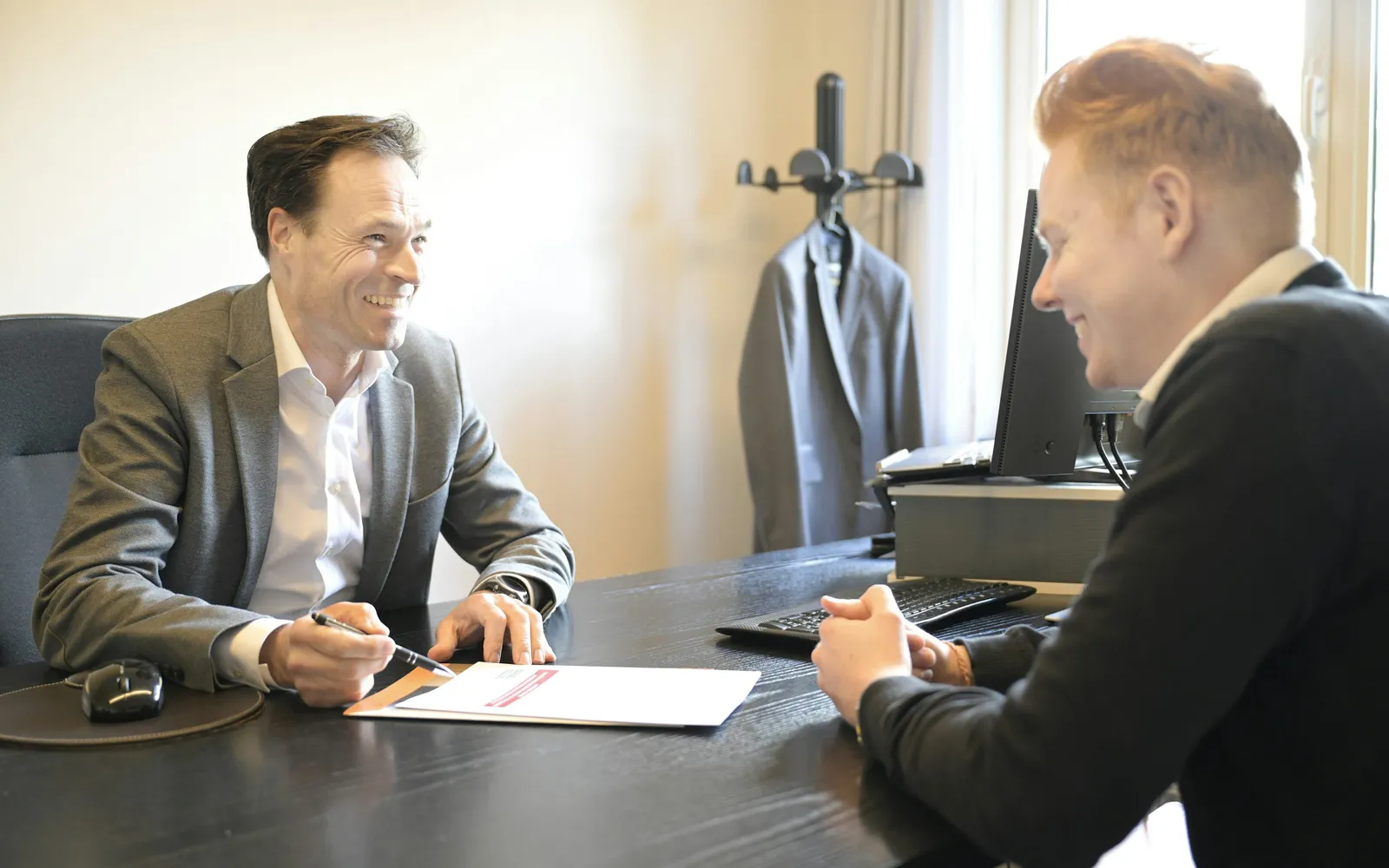 Business owner and a banker smiling over loan documents at an office desk