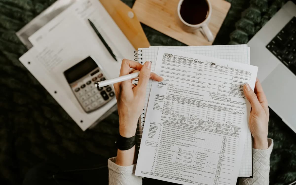 Business owner going through printed tax forms with a calculator and laptop nearby