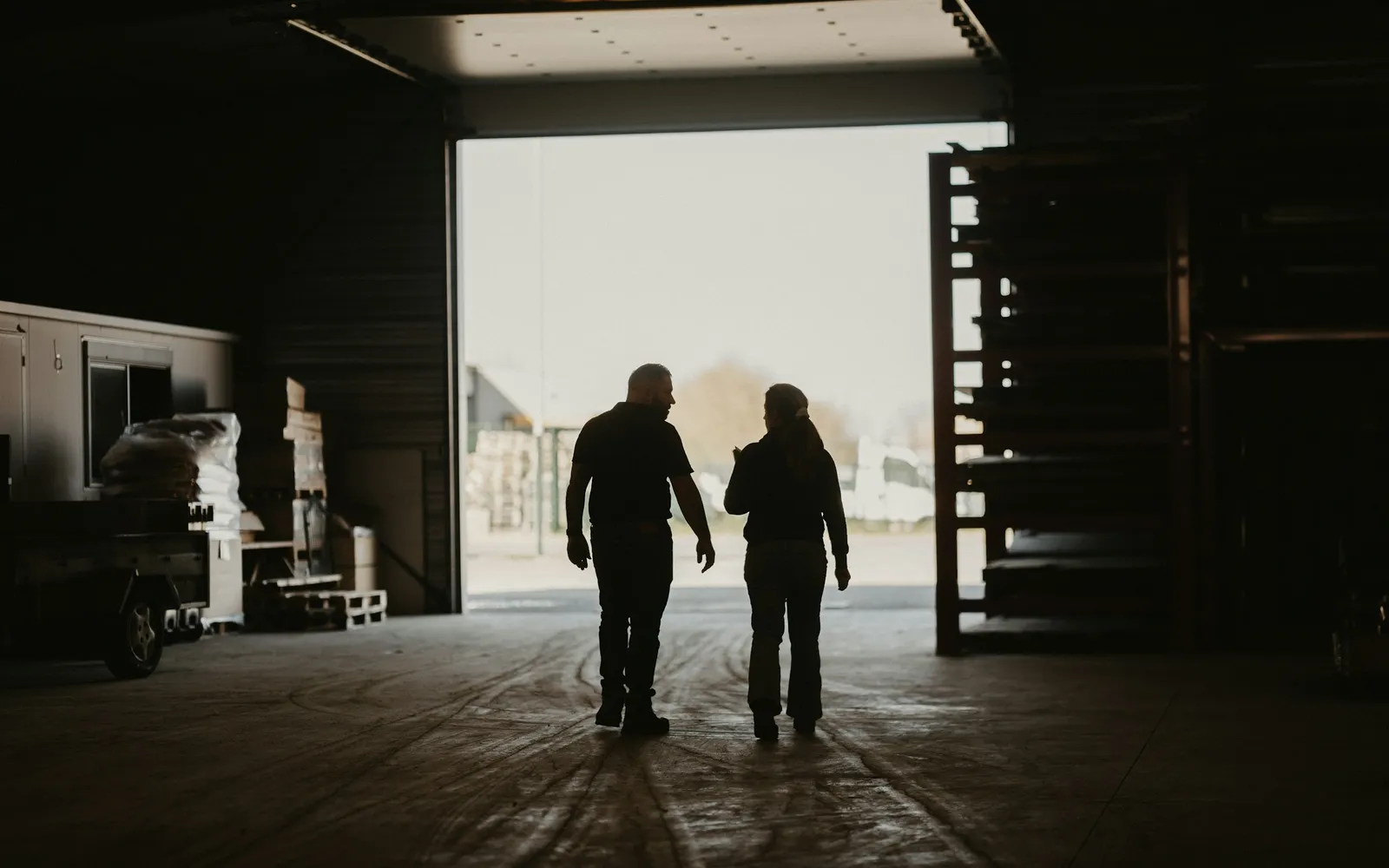 Two business owners walking toward the open bay door of their warehouse building