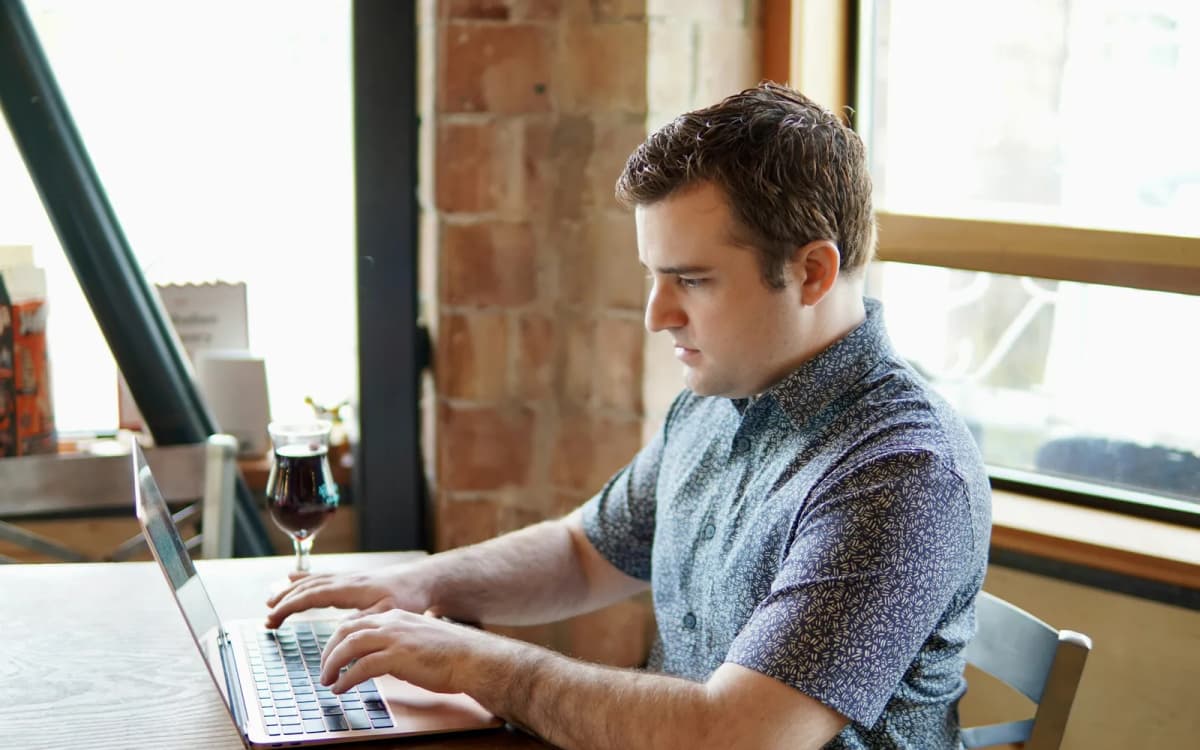 Restaurant owner working on a laptop at a wooden table by the front windows