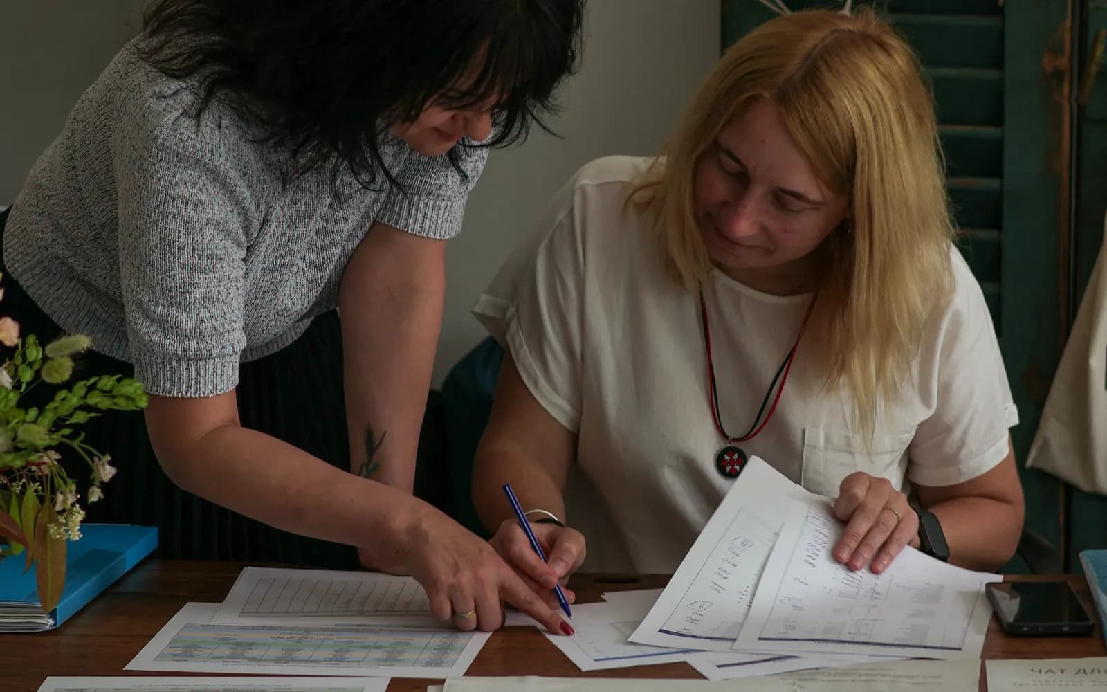 Bookkeeper pointing to figures on printed statements while a business owner takes notes