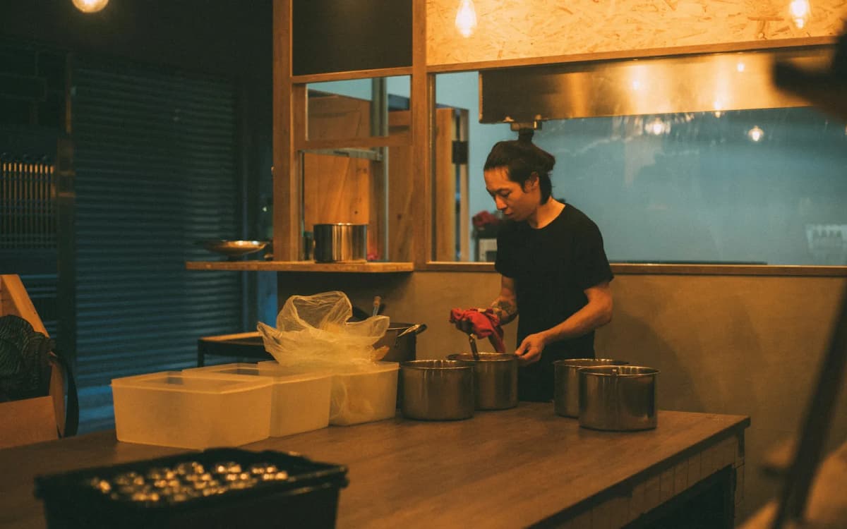 Food truck cook prepping pans of ingredients in a commercial kitchen before service