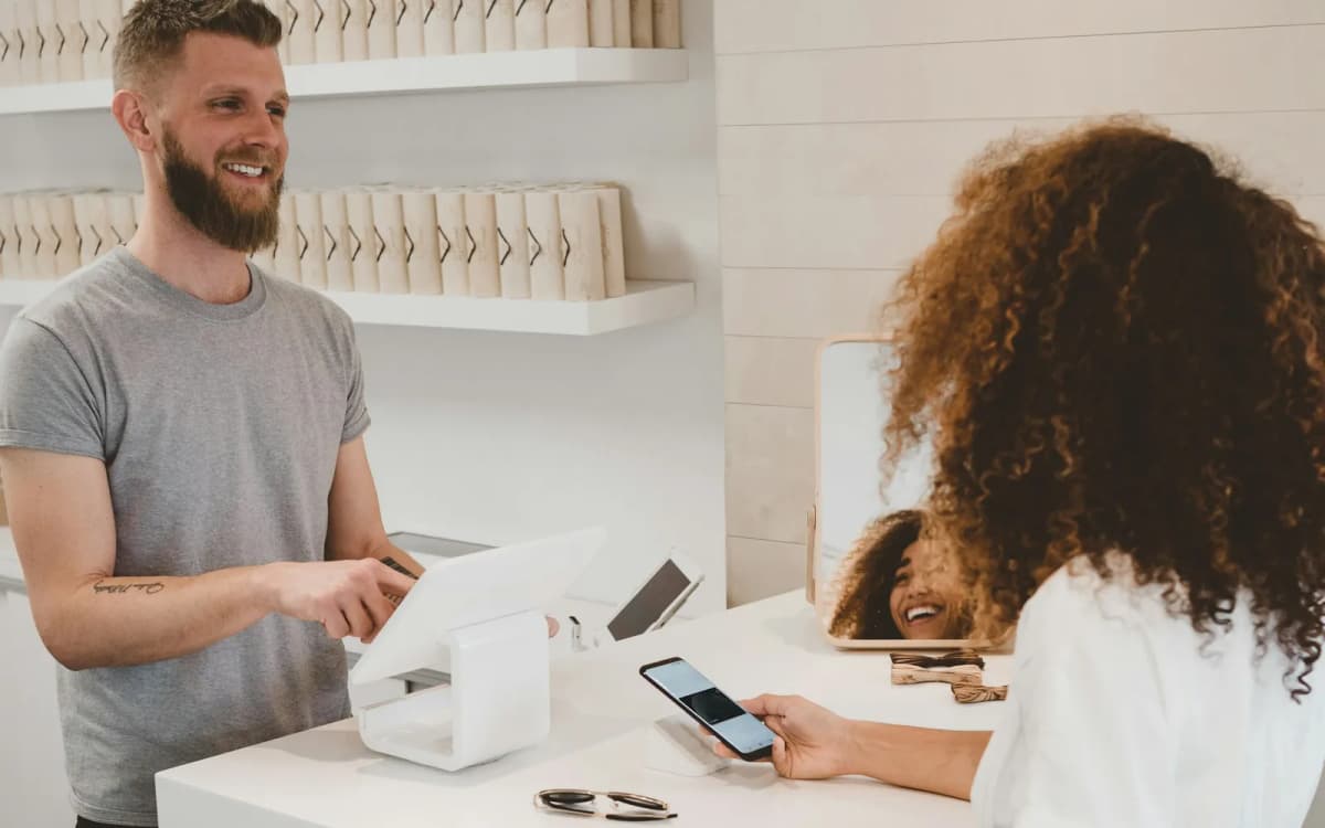Shop owner taking a customer's phone payment at the counter