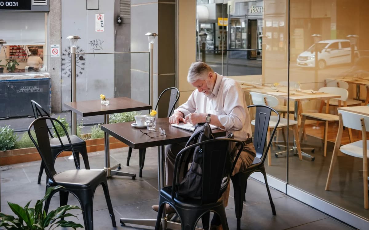 Restaurant owner reading through paperwork at a table in a quiet dining room