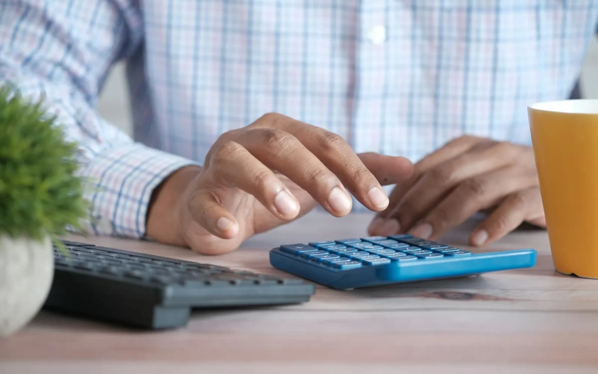 Business owner tapping figures into a calculator at a desk beside a keyboard
