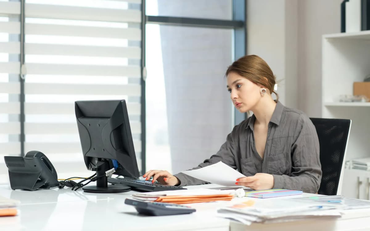 Small business owner going through financial documents at an office desk beside folders and a calculator